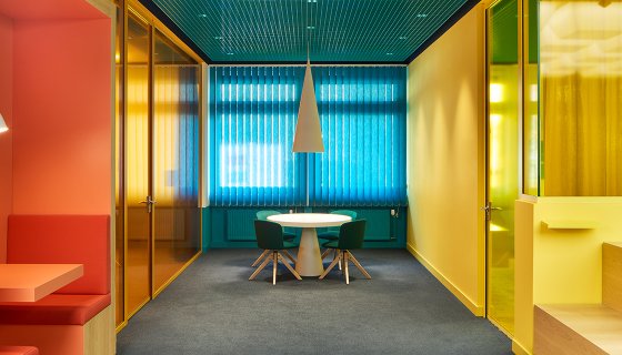 Büroausbau mit farbenfrohen Trennwänden und Decken, inkl. Raum in Raum Systemen sowie Designmöbel passend zum Raumambiente