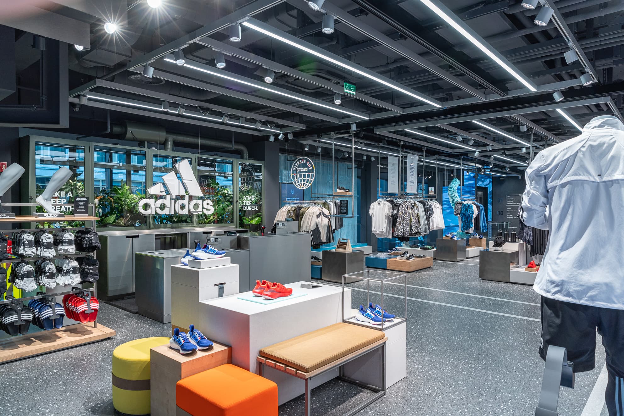 Adidas-Store mit Sportbekleidung, Schuhen und Sandalen auf modernen Verkaufsflächen.