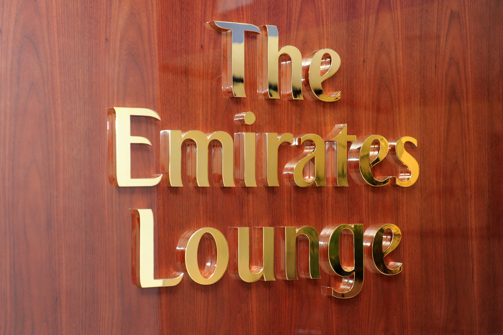 Wandschild mit dem Schriftzug „The Emirates Lounge“ auf warm getönter Holzoberfläche.