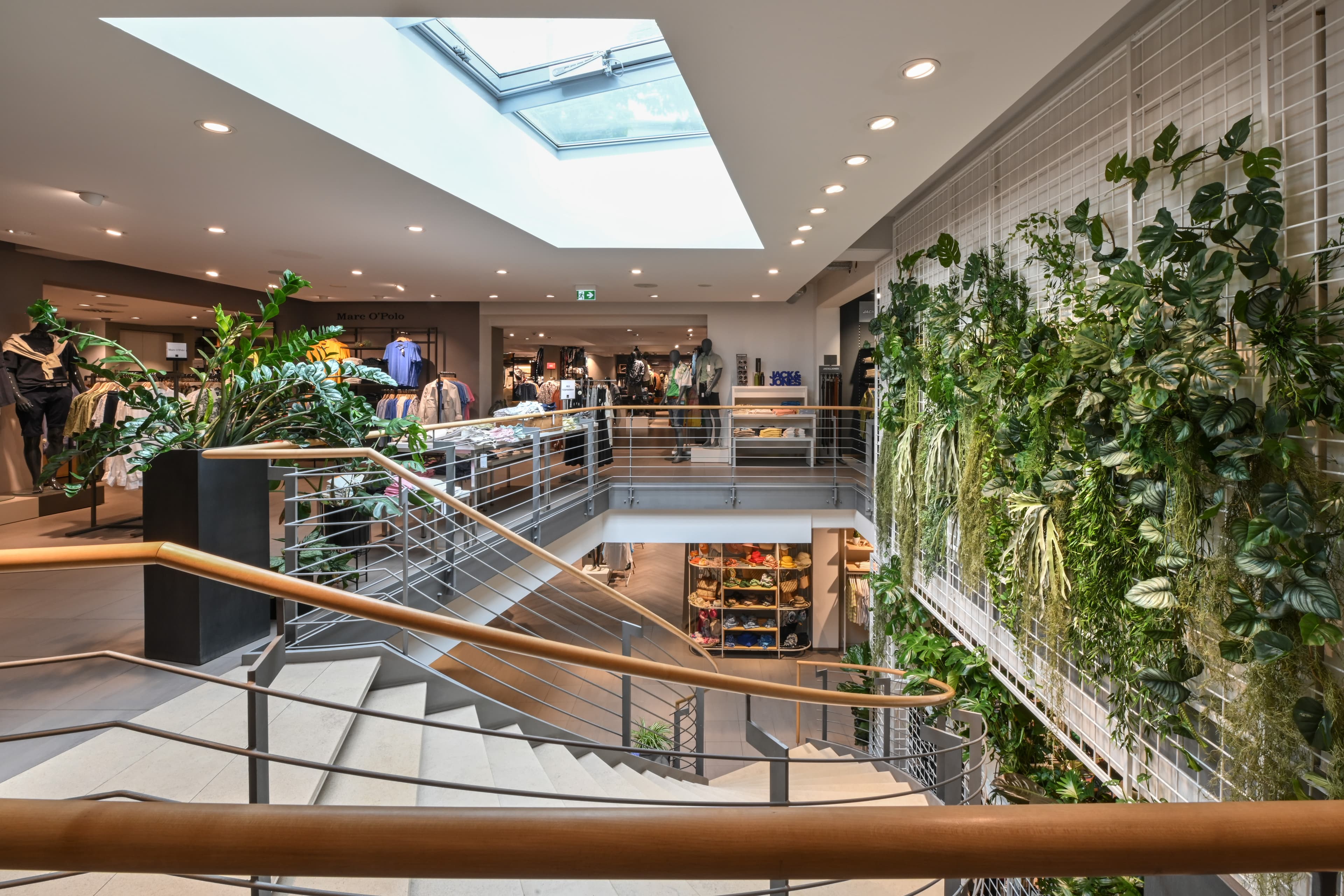 Treppe mit Holzhandlauf, Sitzbereichen und üppiger Begrünung.