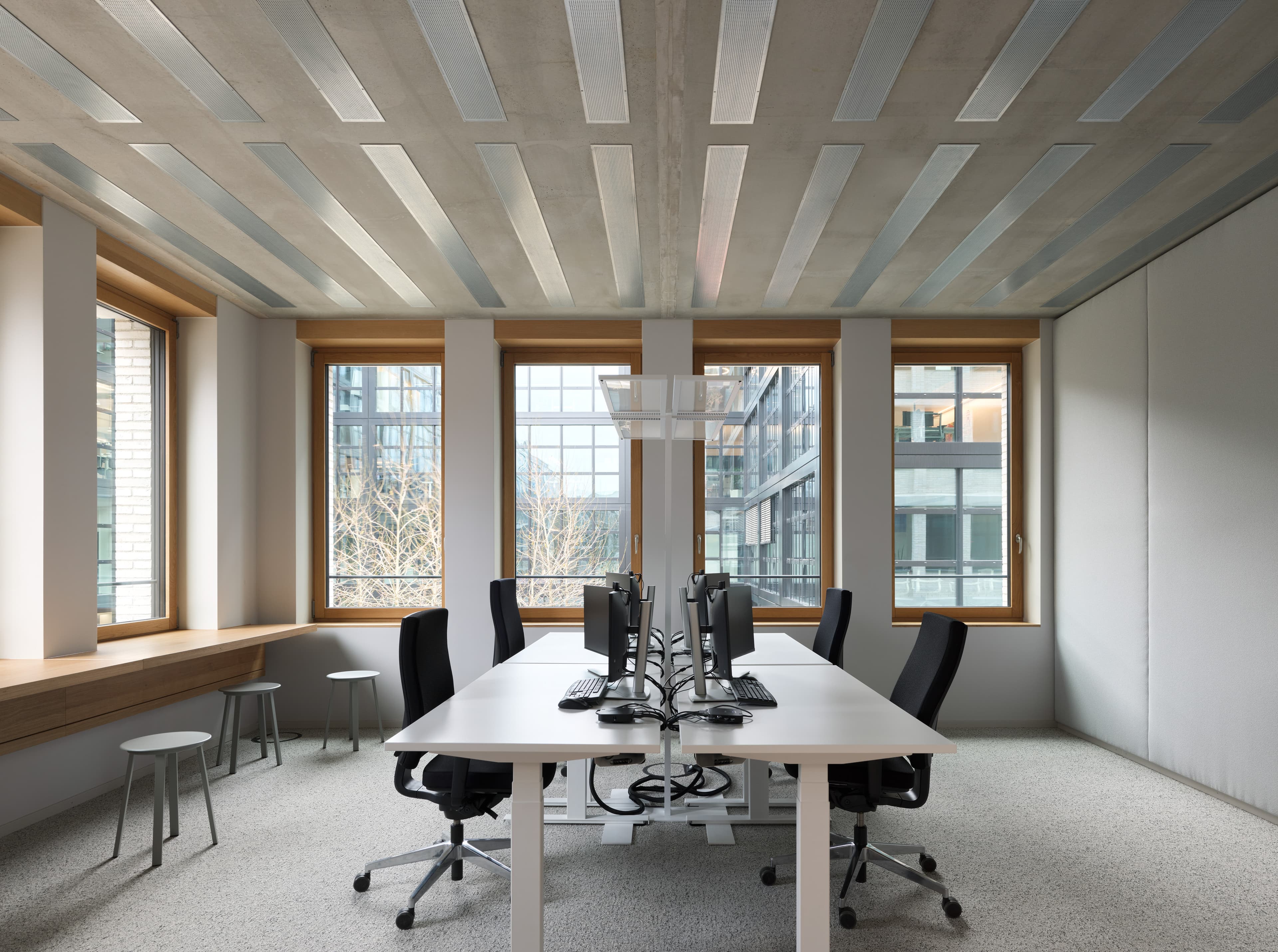 Konferenzraum mit langem Arbeitstisch, Bürostühlen und Fensterfronten.