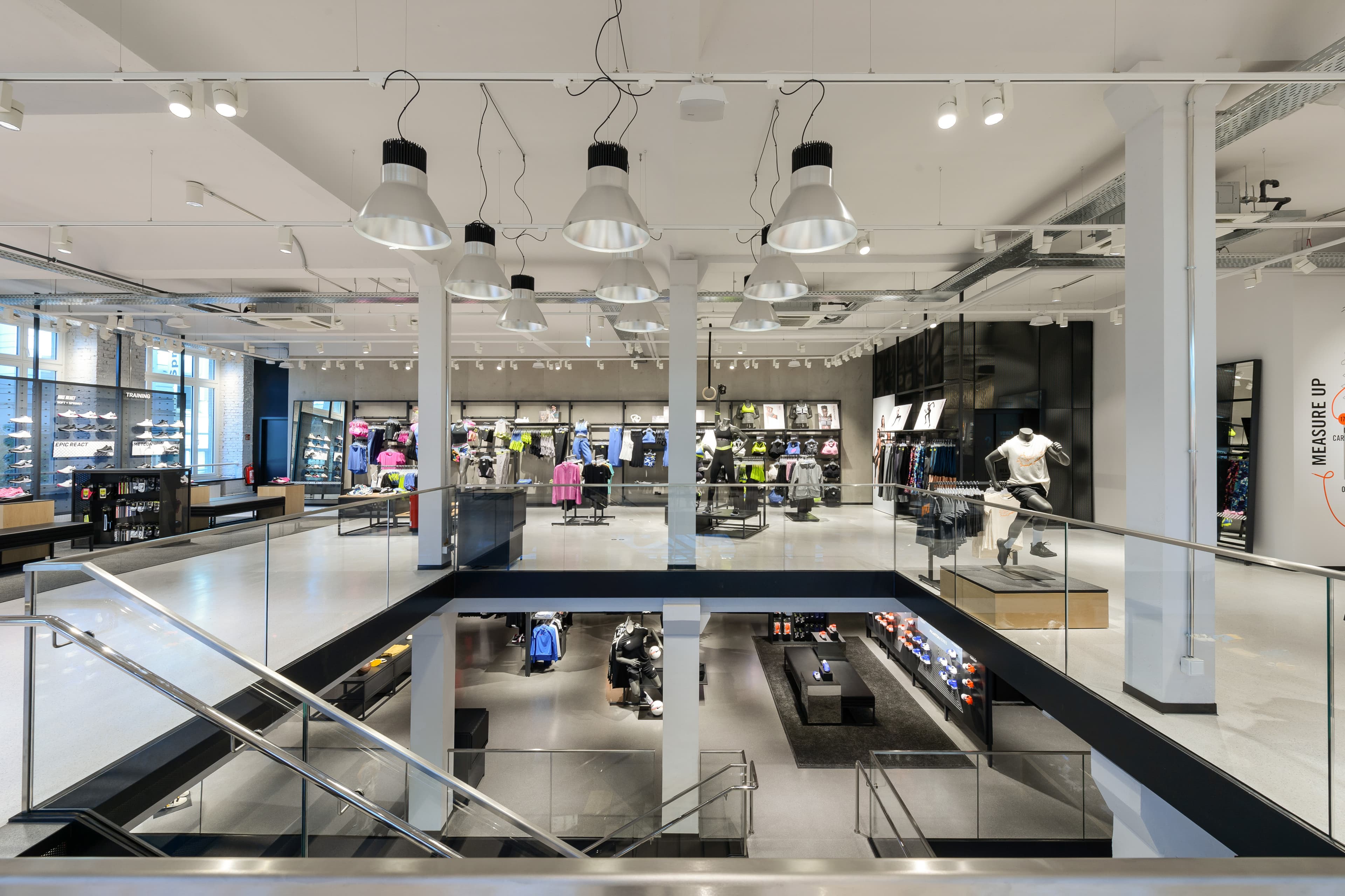Galerie mit Glasgeländern, Blick in den Verkaufsraum und schwarzem Wandmotiv.