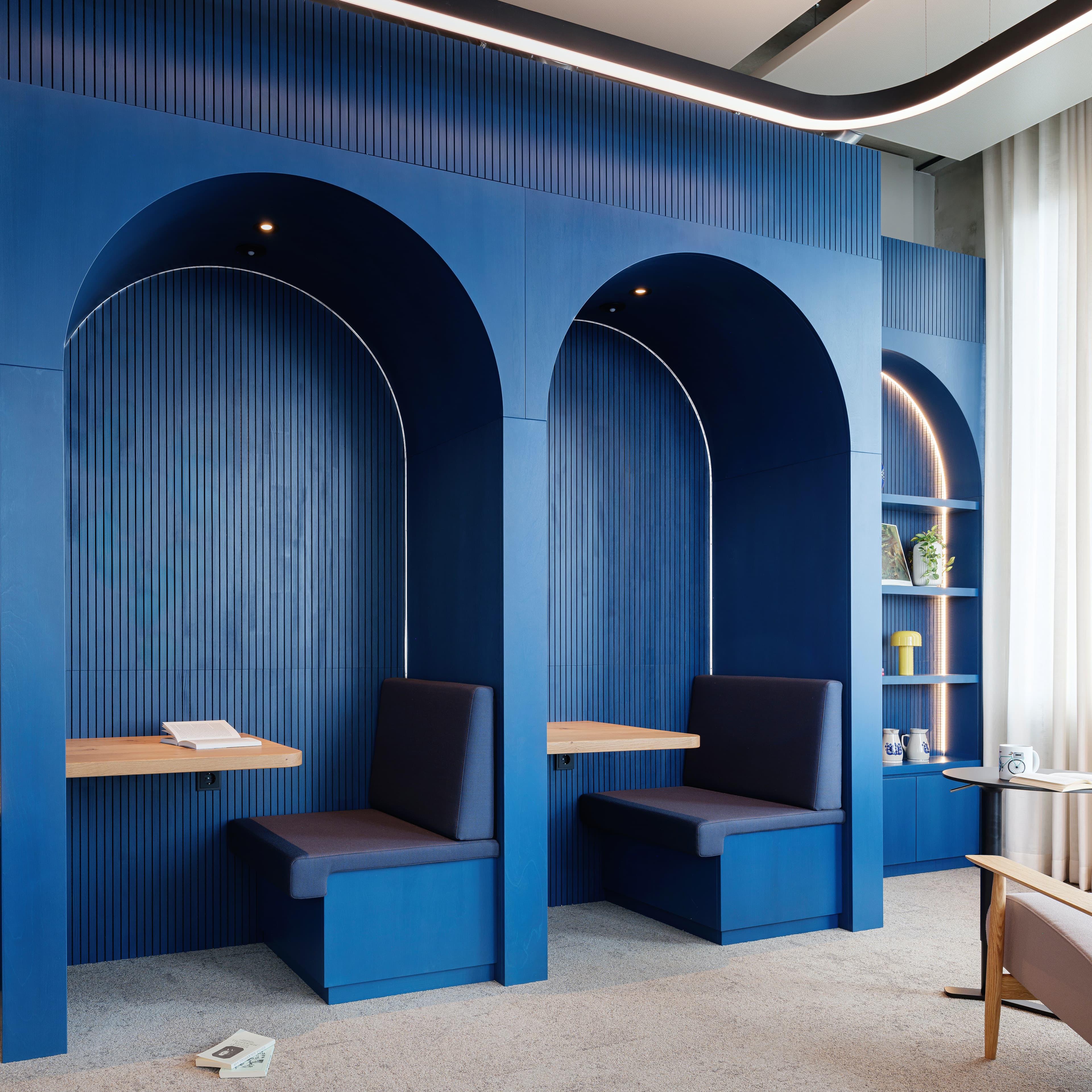 Blaue Sitznischen mit gepolsterten Bänken und kleinen Holztischen.