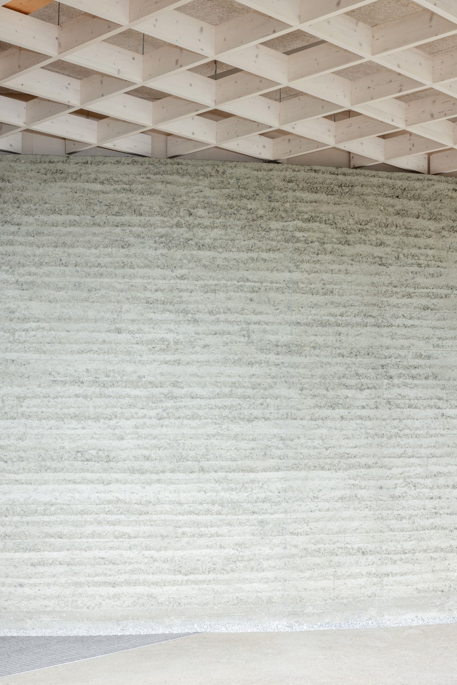Detailansicht einer strukturierten Wand unter einer Holzrasterdecke.