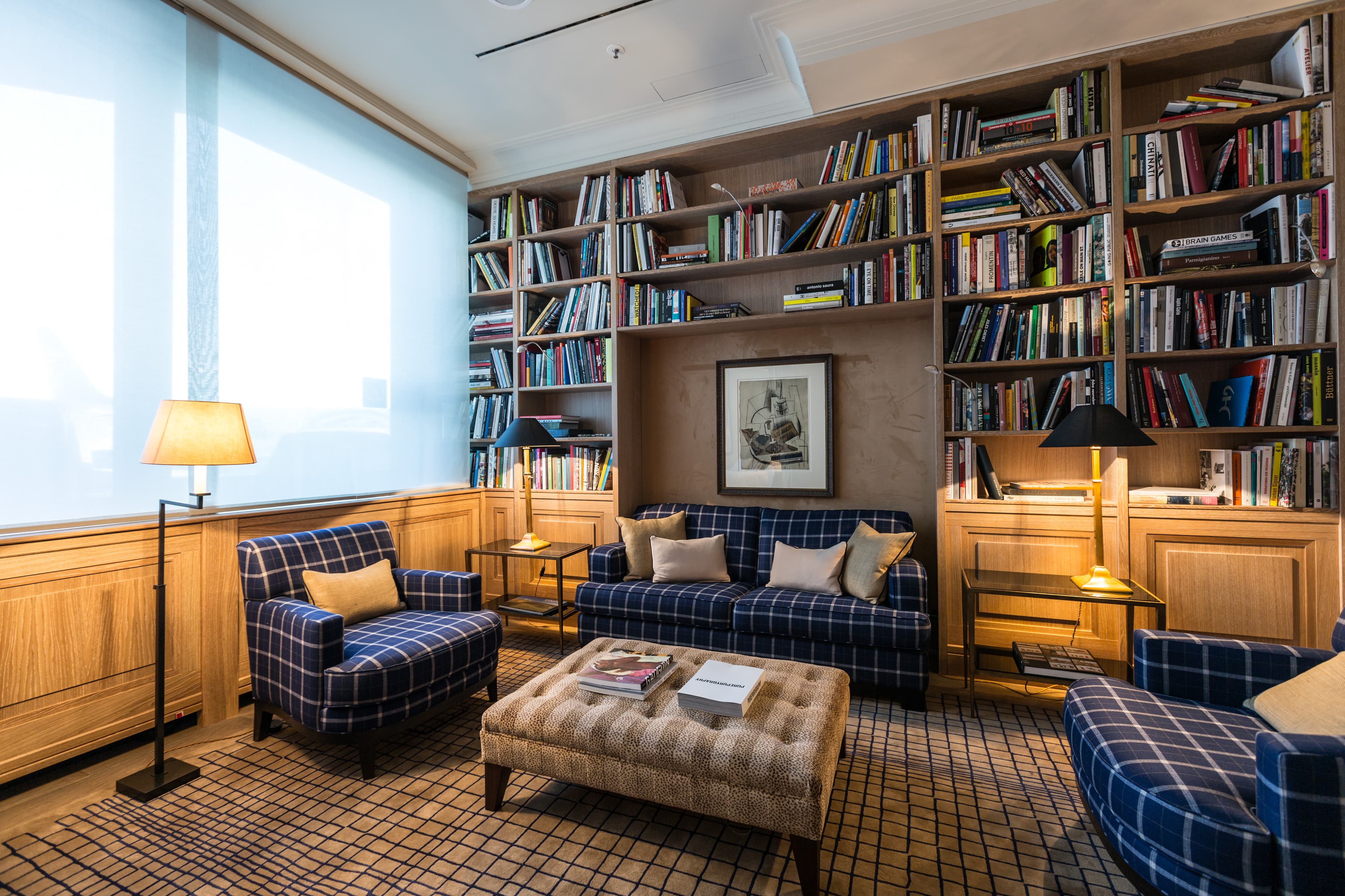 Gemütliche Bibliothekslounge mit Bücherregalen, gepolsterten Sesseln und zentralem Couchtisch.