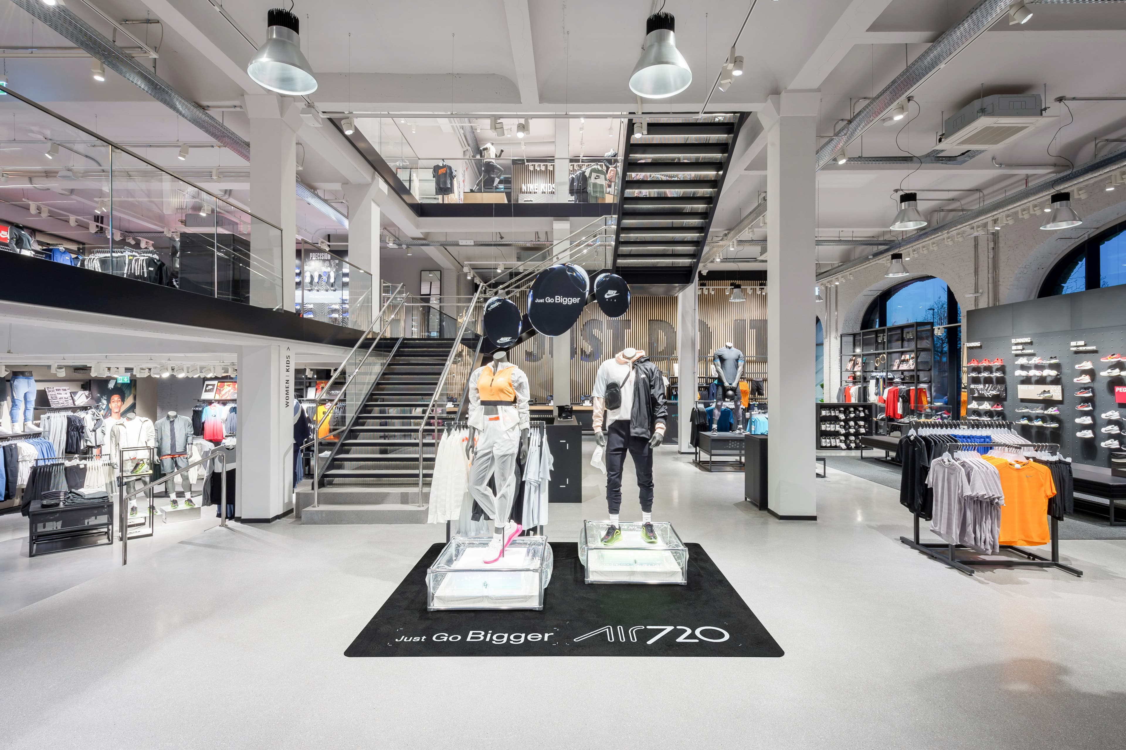 Nike-Store mit Schaufensterpuppen, Sportbekleidung und offener Treppe im Verkaufsraum.
