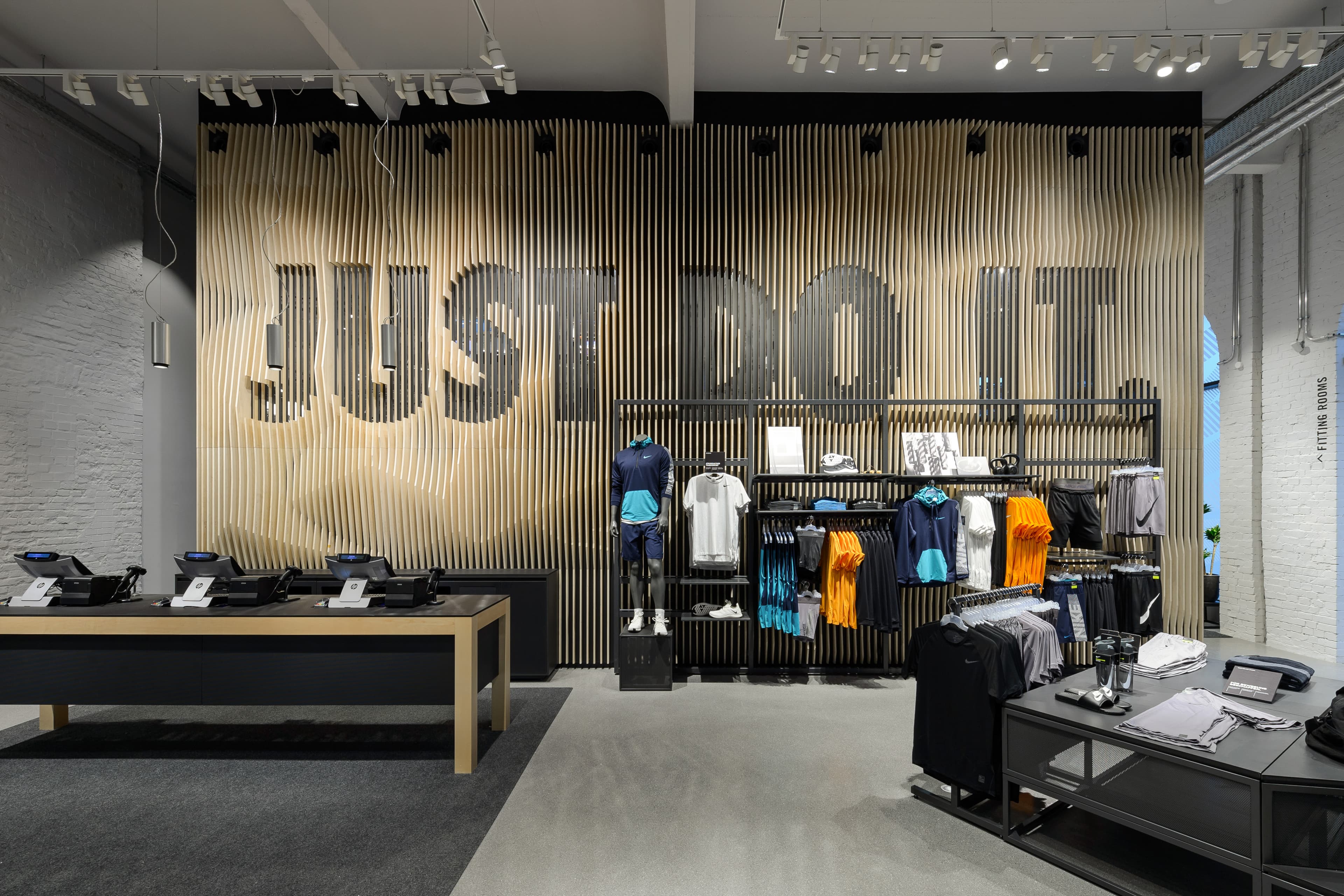 Verkaufsbereich mit großem „Just Do It“-Schriftzug, Sitzbank und Bekleidungsauslagen.