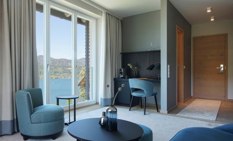 Modernes, hochwertiges Hotelzimmer mit großer Fensterfront und Blick auf den Tegernsee