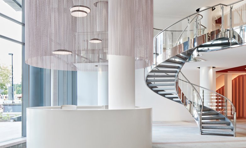 Foyer Häuser der Mode Eschborn, Spiraltreppe, runder Empfangstresen mit metallenem Vorhang darüber