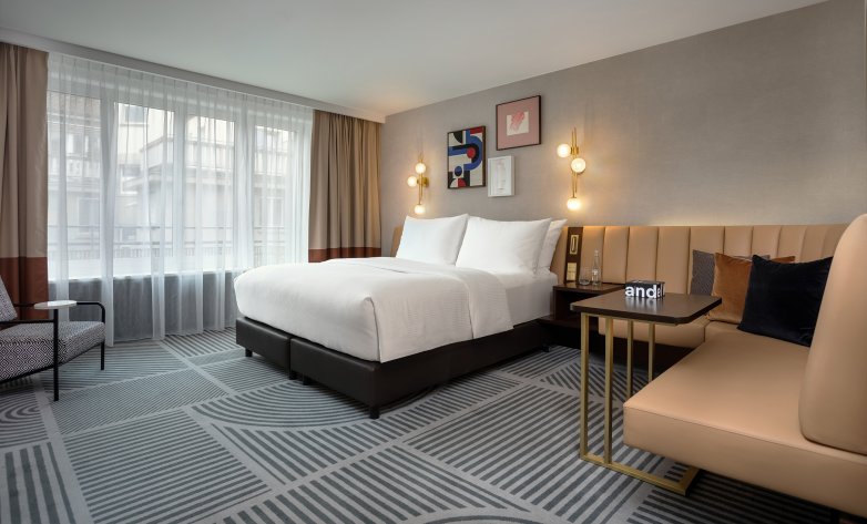 Schlafzimmer Hotel Neues Schloss Zürich, Bett, Eckcouch, Fensterfront mit Gardinen, Beistelltisch, Wandbilder, Wandlampen