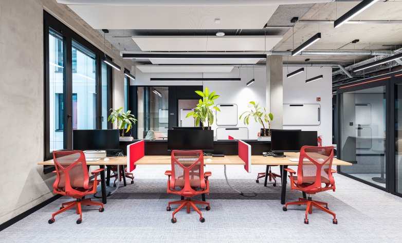 Offene Büroräume mit roten Farbakzenten und Büropflanzen