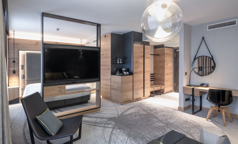 Schlafzimmer mit edlen Teppichboden oder Eichenboden, Vinyltapete und Holztäfelung, inklusive Designmöbel - Hilton Munich Airport