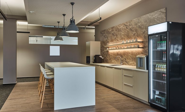 Designküche auf Holzboden mit Aufenthaltsbereich inklusive Sitzmöglichkeiten und indirekte Wandbeleuchtung sowie Holztäfelung - Infor Stuttgart