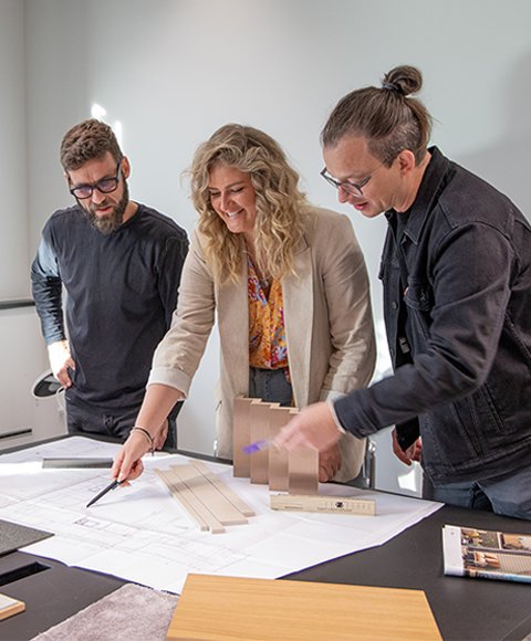 drei Innenarchitekt:innen beraten sich über Projektplänen