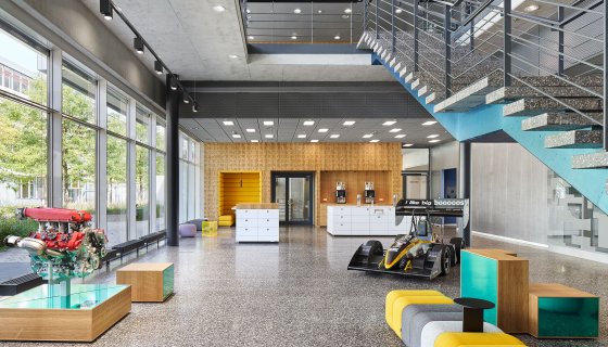 Büroräume Bosch Abstatt, Kaffeeküche, Sitzmöglichkeiten, Rennauto, Fensterfront und Treppe ins zweite Stockwerk