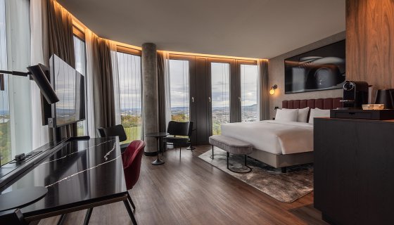 Radisson Blu Stuttgart, Hotelzimmer mit Bett, TV,  Schreibtisch, Kaffeautomat, Stühle mit Tisch
