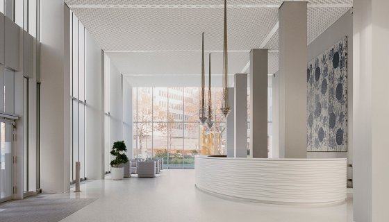 Ein modernes, lichtdurchflutetes Foyer mit hohen Decken und großen Glasfronten. Im Vordergrund steht ein geschwungener Empfangstresen in Weiß, dahinter hohe Säulen und elegante Hängelampen. Helle Farben, klare Linien und dezente Kunst an der Wand verleihen dem Raum eine ruhige, einladende Atmosphäre.
