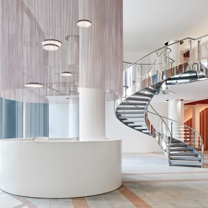 Foyer Häuser der Mode Eschborn, Spiraltreppe, runder Empfangstresen mit metallenem Vorhang darüber