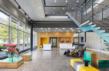 Büroräume Bosch Abstatt, Kaffeeküche, Sitzmöglichkeiten, Rennauto, Fensterfront und Treppe ins zweite Stockwerk