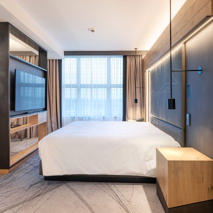 Schlafzimmer mit edlen Eichenboden, Vinyltapete und Fernseher in Holztäfelung, inklusive Designmöbel - Hilton Munich Airport